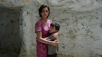 Movie still from “Pain and Glory” (2019), directed by Pedro Almodóvar – A woman and a boy are standing in front of a stone wall; Medium shot, High angle