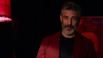 Movie still from “Pain and Glory” (2019), directed by Pedro Almodóvar – A man in a red jacket standing in front of a black background; Close Up shot, Over the shoulder angle