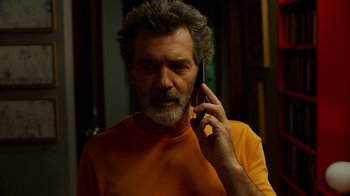 Movie still from “Pain and Glory” (2019), directed by Pedro Almodóvar – A man in an orange shirt talking on a cell phone; Close Up shot, Low angle