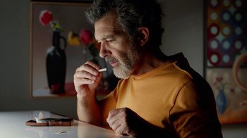 Movie still from “Pain and Glory” (2019), directed by Pedro Almodóvar – A person sitting at a table; Medium shot, Low angle