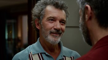 Movie still from “Pain and Glory” (2019), directed by Pedro Almodóvar – An older man with grey hair is smiling; Close Up shot, Over the shoulder angle