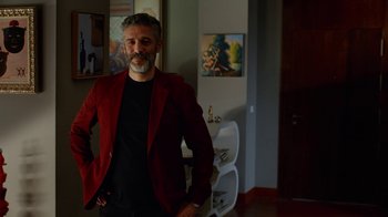 Movie still from “Pain and Glory” (2019), directed by Pedro Almodóvar – A man in a red jacket standing in front of a painting; Medium shot, Over the shoulder angle
