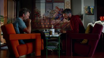 Movie still from “Pain and Glory” (2019), directed by Pedro Almodóvar – Two men are sitting in a living room; Medium shot, Over the shoulder angle