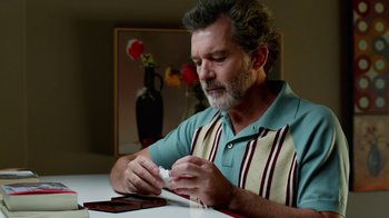 Movie still from “Pain and Glory” (2019), directed by Pedro Almodóvar – An older man sitting at a table with a knife in his hand; Close Up shot, Low angle