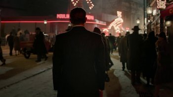 Movie still from “Papillon” (2017), directed by Michael Noer – A crowd of people walking down a street at night; Medium shot, Low angle