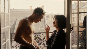 Movie still from “Papillon” (2017), directed by Michael Noer – A man and a woman standing next to each other on a balcony; Medium shot, Over the shoulder angle