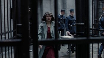 Movie still from “Papillon” (2017), directed by Michael Noer – A woman in a red dress and a man in a blue coat; Wide shot, Over the shoulder angle