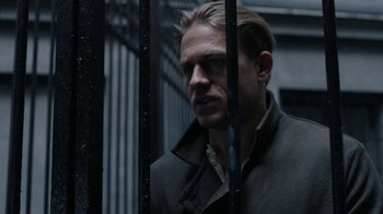 Movie still from “Papillon” (2017), directed by Michael Noer – A person behind a metal fence; Close Up shot, Over the shoulder angle