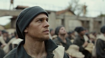 Movie still from “Papillon” (2017), directed by Michael Noer – A person wearing a hat; Close Up shot, Low angle