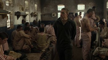 Movie still from “Papillon” (2017), directed by Michael Noer – A group of people sitting around in a room; Medium shot, Over the shoulder angle