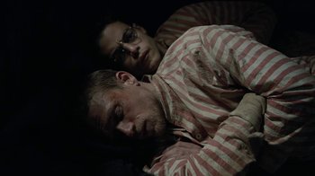 Movie still from “Papillon” (2017), directed by Michael Noer – A man and a woman laying on the ground; Medium shot, High angle
