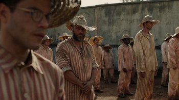 Movie still from “Papillon” (2017), directed by Michael Noer – A group of men in striped shirts and straw hats; Medium shot, Over the shoulder angle