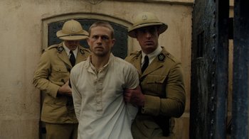 Movie still from “Papillon” (2017), directed by Michael Noer – A group of men standing next to each other; Medium shot, Over the shoulder angle