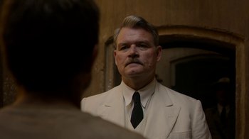 Movie still from “Papillon” (2017), directed by Michael Noer – A man in a suit and tie looking into a mirror; Close Up shot, Low angle