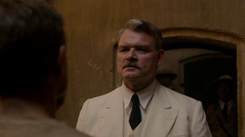Movie still from “Papillon” (2017), directed by Michael Noer – A man wearing a suit and tie looking at a mirror; Close Up shot, Over the shoulder angle