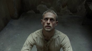 Movie still from “Papillon” (2017), directed by Michael Noer – A person wearing a shirt with dirt all over it; Close Up shot, Overhead angle