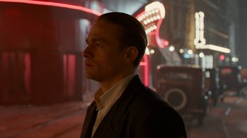 Movie still from “Papillon” (2017), directed by Michael Noer – A person wearing a suit and tie; Close Up shot, Low angle