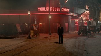 Movie still from “Papillon” (2017), directed by Michael Noer – A man standing in front of a movie theater at night; Extreme Wide shot, High angle