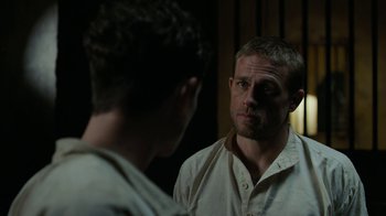Movie still from “Papillon” (2017), directed by Michael Noer – A man looking at himself in the mirror while standing next to another man; Close Up shot, Over the shoulder angle