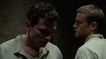 Movie still from “Papillon” (2017), directed by Michael Noer – Two men standing next to each other in a dark room; Close Up shot, Over the shoulder angle