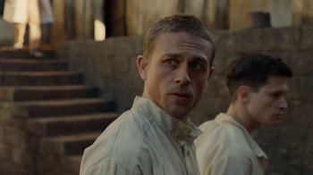 Movie still from “Papillon” (2017), directed by Michael Noer – A person wearing a white shirt; Close Up shot, Over the shoulder angle