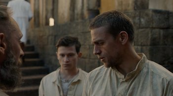 Movie still from “Papillon” (2017), directed by Michael Noer – Two men standing next to each other in front of a brick wall; Close Up shot, Over the shoulder angle