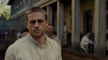 Movie still from “Papillon” (2017), directed by Michael Noer – A person wearing a white shirt; Close Up shot, Over the shoulder angle