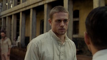 Movie still from “Papillon” (2017), directed by Michael Noer – A person wearing a white shirt; Close Up shot, Over the shoulder angle
