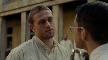 Movie still from “Papillon” (2017), directed by Michael Noer – A man in a white dress shirt is talking to another man; Close Up shot, Over the shoulder angle