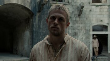 Movie still from “Papillon” (2017), directed by Michael Noer – A person wearing a striped shirt; Close Up shot, Low angle