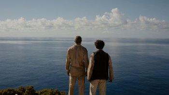 Movie still from “Papillon” (2017), directed by Michael Noer – Two men standing on a cliff looking out at the ocean; Wide shot, High angle