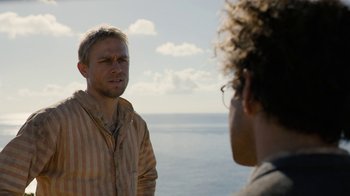 Movie still from “Papillon” (2017), directed by Michael Noer – Two people standing on the beach looking at each other; Close Up shot, Over the shoulder angle