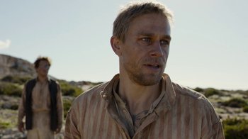 Movie still from “Papillon” (2017), directed by Michael Noer – A person wearing a striped shirt; Close Up shot, Over the shoulder angle
