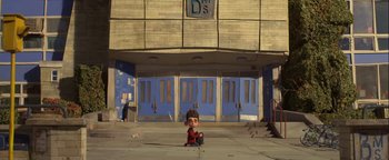 Movie still from “ParaNorman” (2012), directed by Sam Fell – A boy sitting on the ground in front of a building; Extreme Wide shot, Low angle