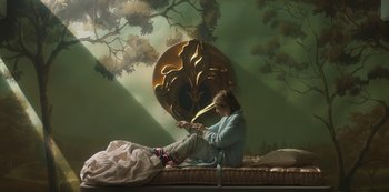 Movie still from “Paradise Hills” (2019), directed by Alice Waddington – A woman sitting on a bed in front of a painting; Wide shot, Low angle