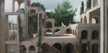 Movie still from “Paradise Hills” (2019), directed by Alice Waddington – A man is sitting on the steps of a building; Extreme Wide shot, High angle