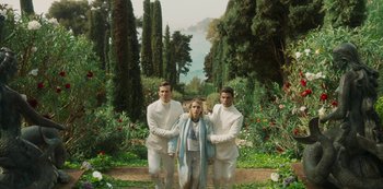 Movie still from “Paradise Hills” (2019), directed by Alice Waddington – A woman standing between two men in white suits; Wide shot, High angle