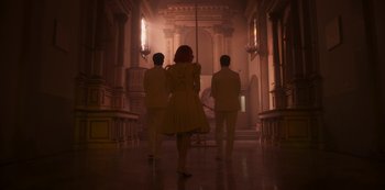 Movie still from “Paradise Hills” (2019), directed by Alice Waddington – A group of three people walking down a hall way; Wide shot, Low angle