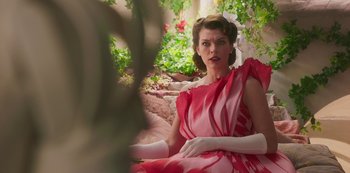 Movie still from “Paradise Hills” (2019), directed by Alice Waddington – A woman in a pink dress sitting in a garden; Medium shot, Over the shoulder angle
