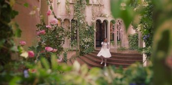 Movie still from “Paradise Hills” (2019), directed by Alice Waddington – A woman in a white dress standing on a set of stairs; Extreme Wide shot, High angle