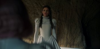 Movie still from “Paradise Hills” (2019), directed by Alice Waddington – A woman in a white dress standing in front of a rock wall; Close Up shot, Over the shoulder angle