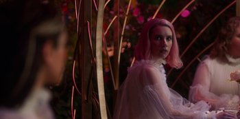 Movie still from “Paradise Hills” (2019), directed by Alice Waddington – A woman with pink hair standing next to a tree; Medium shot, Over the shoulder angle
