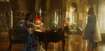 Movie still from “Paradise Hills” (2019), directed by Alice Waddington – A woman sitting at a table in a room; Wide shot, Low angle
