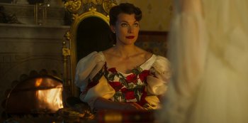Movie still from “Paradise Hills” (2019), directed by Alice Waddington – A woman sitting in front of a mirror wearing a dress; Medium shot, Over the shoulder angle