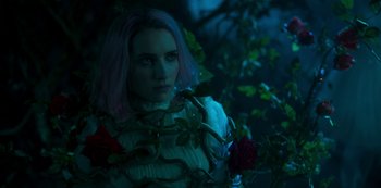 Movie still from “Paradise Hills” (2019), directed by Alice Waddington – A woman with pink hair standing next to a rose bush; Close Up shot, High angle