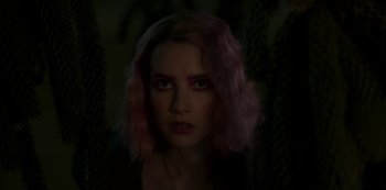 Movie still from “Paradise Hills” (2019), directed by Alice Waddington – A woman with pink hair is looking at the camera; Close Up shot, Over the shoulder angle