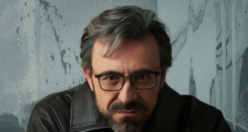 Movie still from “Parallel Mothers” (2021), directed by Pedro Almodóvar – A person wearing glasses and a leather jacket; Close Up shot, Low angle
