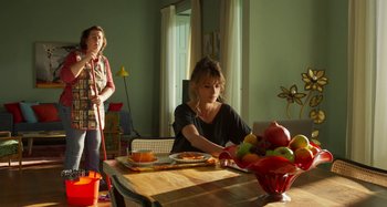 Movie still from “Parallel Mothers” (2021), directed by Pedro Almodóvar – A woman sitting at a table with a bowl of fruit; Medium shot, Over the shoulder angle
