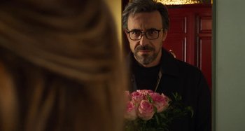 Movie still from “Parallel Mothers” (2021), directed by Pedro Almodóvar – A man holding a bouquet of pink roses; Close Up shot, Over the shoulder angle