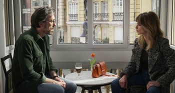 Movie still from “Parallel Mothers” (2021), directed by Pedro Almodóvar – Two people sitting at a table with a glass of wine; Medium shot, Over the shoulder angle